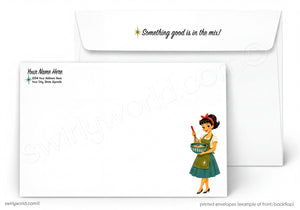 A white stationery set shown on a light gray background, featuring a rectangular letterhead envelope with a retro-style illustration of a woman in a green dress holding a bowl, and a matching flap envelope behind it with the phrase 'Something good is in the mix!' printed on it.