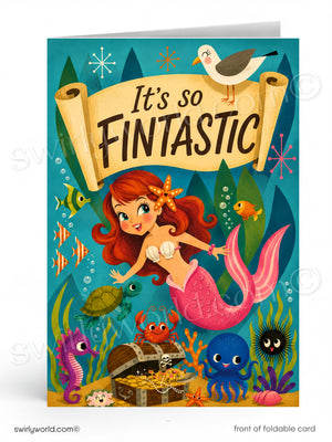 A colorful folded greeting card featuring an underwater mermaid scene with the text 'It's so FINTANTIC' on a scroll banner. The card shows a mermaid with red hair and a pink tail, surrounded by fish, a crab, a treasure chest, a seahorse, a blue octopus, a black sea urchin, and a seagull at the top.