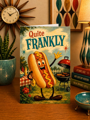 a greeting card with a cartoon hot dog character on it, placed on a wooden surface.