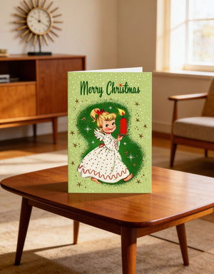 A green Christmas card featuring a smiling girl in a white dress holding a red candle, with the text "Merry Christmas" displayed on the card.