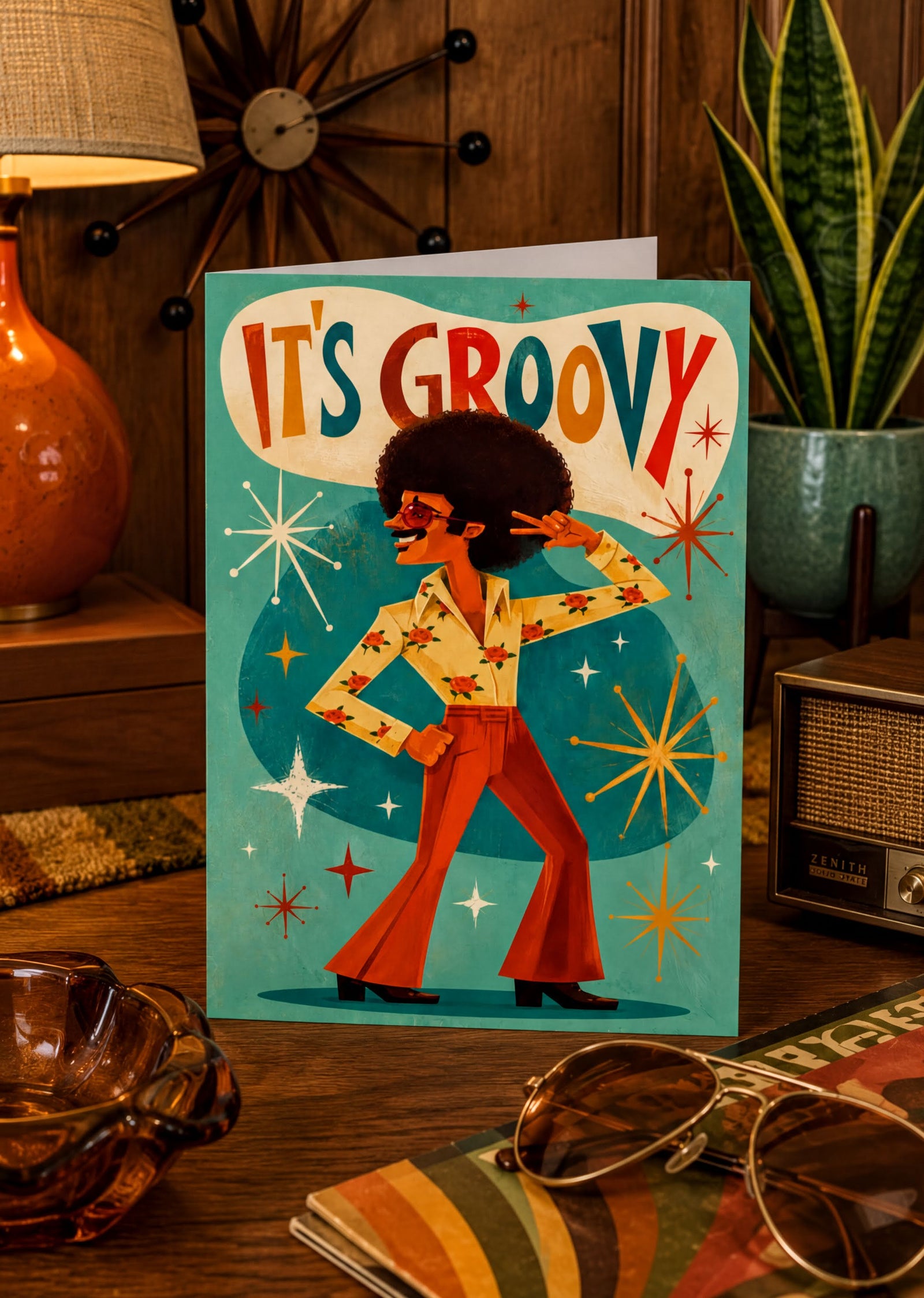 The image is a colorful illustration of a man with a large afro hairstyle, wearing a yellow shirt with red and orange flowers, and red pants. He is dancing and holding a peace sign. The background features a teal color with stars and a speech bubble that says "It's groovy".