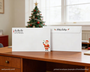 Two printed holiday greeting envelopes sit on a wooden desk, with a decorated Christmas tree visible in the background.