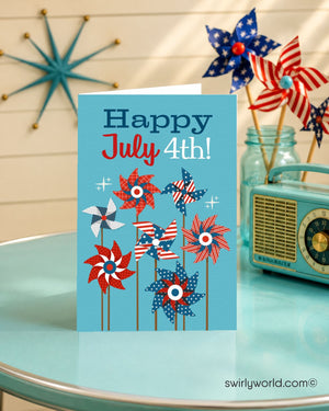 A blue greeting card with a patriotic design of pinwheels and American flags, placed on a table with a turquoise tablecloth. In the background, there are American pinwheels and a turquoise radio.