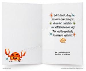 An open greeting card with a white interior. The left panel shows a smiling orange crab illustration with blue starburst accents.