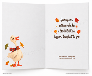 An open greeting card with a white background, featuring a cartoon duck wearing a red plaid scarf on the left and autumn-themed text with orange and red leaves on the right.