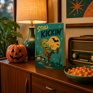 a Halloween-themed card with a jack-in-the-box, a pumpkin, a lamp, a radio, and a bowl of candy on a wooden table.