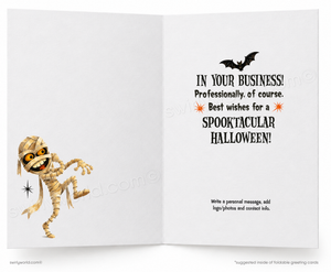 An open folding greeting card shown front and back. The left panel features a cartoon mummy with glowing yellow eyes and a small black bat above.