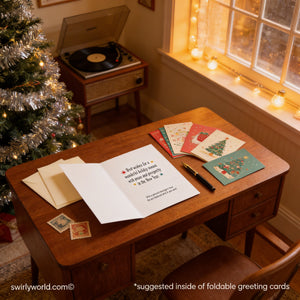 A wooden desk with a record player, a stack of greeting cards, and a handwritten note, all set against the backdrop of a Christmas tree and string lights.