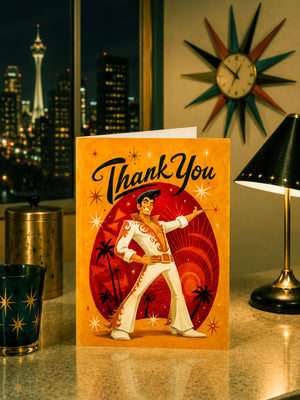 a card with a cartoon illustration of a man in a white suit and hat, surrounded by stars and palm trees, with a message that says "Thank You". The card is placed on a table, with a lamp and a clock visible in the background.