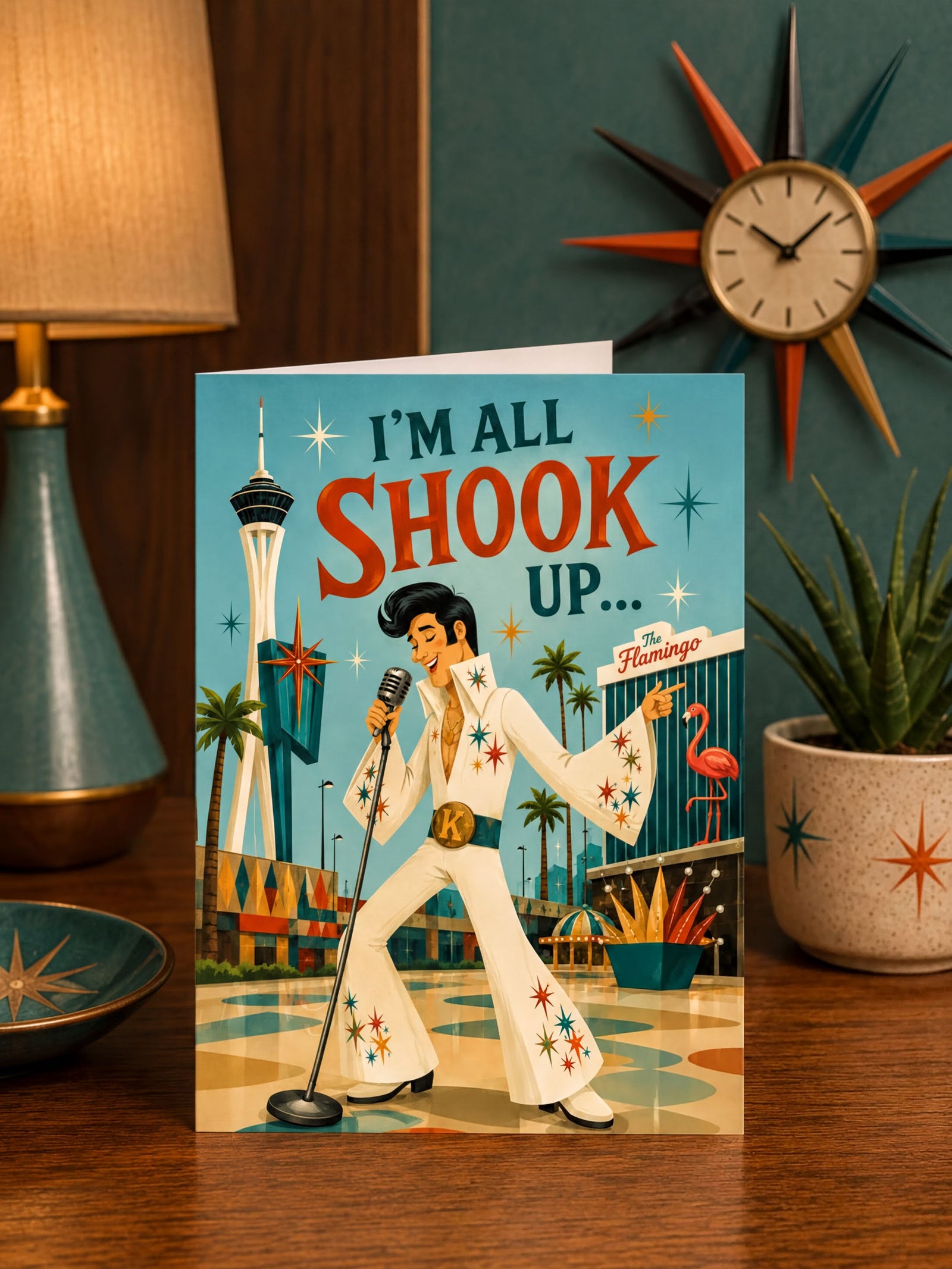 A folded greeting card featuring a retro-style illustration of Elvis Presley singing at The Flamingo in Las Vegas, with the text 'I'M ALL SHOOK UP.