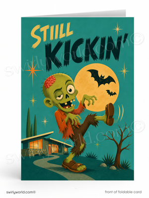 The image is a colorful illustration of a zombie character with a large skull on its head, wearing a red shirt and brown pants, and holding a bat in its hand. The background features a house, trees, and a full moon, creating a spooky and festive atmosphere. The text "STILL KICKIN'" is prominently displayed, and the image is described as a "front of foldable card" with a "swirlworld.com" watermark.