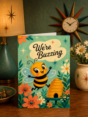 A greeting card featuring a cartoon bee surrounded by flowers and a beehive, with the text "We're Buzzing" displayed prominently.