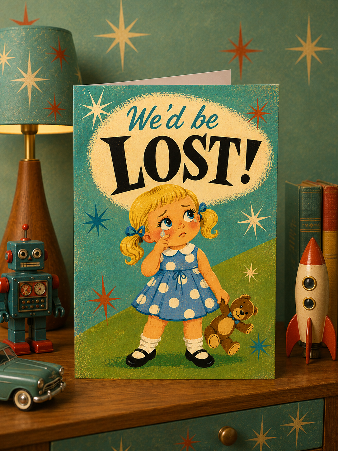 A vintage-style foldable card featuring an illustration of a sad blonde girl in a blue polka-dot dress standing on green grass, holding a teddy bear, with the text 'We'd be LOST!' above her against a teal starry background.