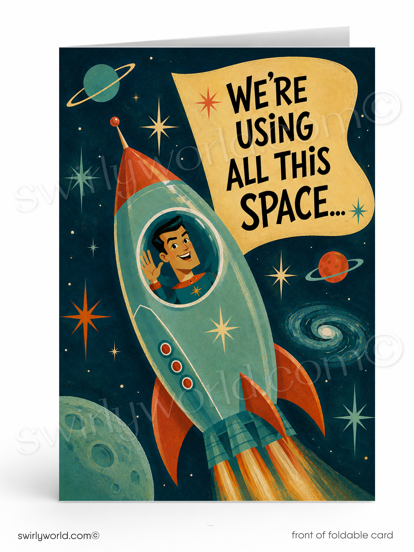 A folded greeting card shown upright on a white background. The card front features a retro space illustration with a teal rocket ship, planets, stars, and a yellow banner reading “WE'RE USING ALL THIS SPACE.
