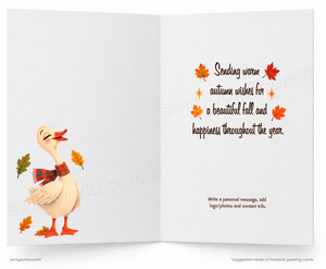 An open greeting card with a white background, featuring a cartoon duck wearing a red plaid scarf on the left and autumn-themed text with orange and red leaves on the right.