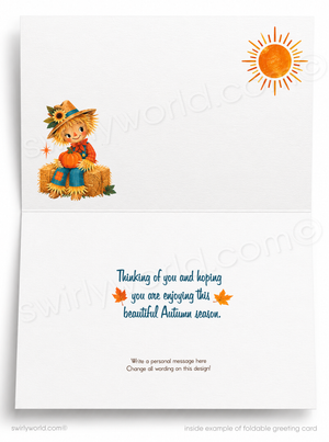 Foldable greeting card shown open, with an autumn-themed illustration on the left side featuring a scarecrow, a yellow sun in the upper right, and blue and orange text on the inside panel reading, 'Thinking of you and hoping you are enjoying this beautiful Autumn season.'.