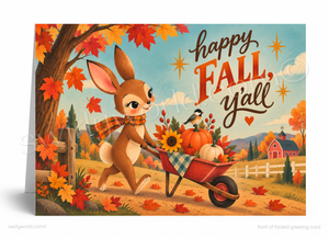 A folded greeting card shown standing upright, featuring a whimsical autumn illustration of a rabbit pushing a wheelbarrow filled with pumpkins, sunflowers, and fall foliage. The card has the text 'happy FALL, y'all' in large decorative lettering, with a small barn, trees, and blue sky in the background.
