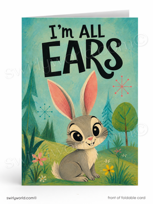A folded greeting card shown front-facing on a white background. The card features the phrase “I’m ALL EARS” in large black lettering above an illustrated gray rabbit with pink inner ears, sitting in a grassy field with trees and small flowers.