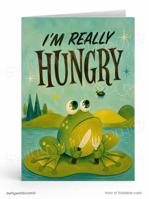 A folded greeting card shown upright on a white background. The card features a whimsical illustration of a green frog sitting on a lily pad and holding a knife and fork, with the text 'I'M REALLY HUNGRY' above it.