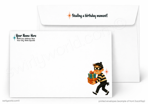 Custom printed white envelopes shown on a light gray background, with one envelope displaying the back side featuring a cartoon burglar carrying a gift and the text 'Stealing a birthday moment!' and 'Your Name Here', and the other showing the front side with placeholder text.