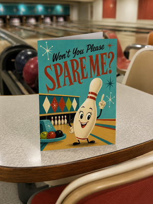 A retro-style bowling-themed greeting card that reads 'Won't You Please SPARE ME?' is standing on a bowling alley table. The card features a smiling bowling pin character and bowling pins, with a blurred bowling alley background visible behind it.