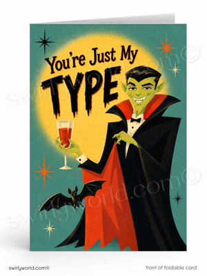 A folded greeting card shown front-on against a white background. The card features a retro-style illustration of a green vampire in a black cape with a red collar, holding a glass of red liquid, with the text 'You're Just My TYPE' above him.